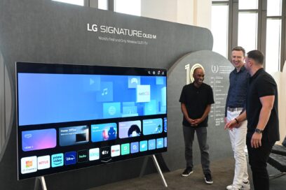 Three men smiling as they take a closer look at an LG SIGNATURE OLED M3 model displayed at the webOS Partner Summit event