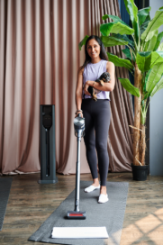 A woman using LG CordZero vacuum to clean up her space after working out while holding a puppy in her arms