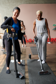 Two participants of the puppy yoga class using LG CordZero vacuum to clean up