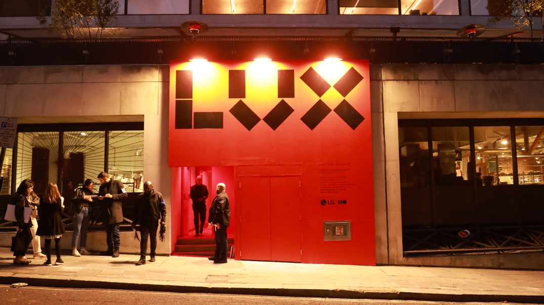 Visitors queued in front of a building’s entrance painted in red, waiting to view a special exhibition