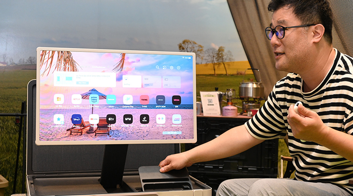 An LG representative showing connectivity ports at the bottom of the LG StanbyME Go model in landscape mode
