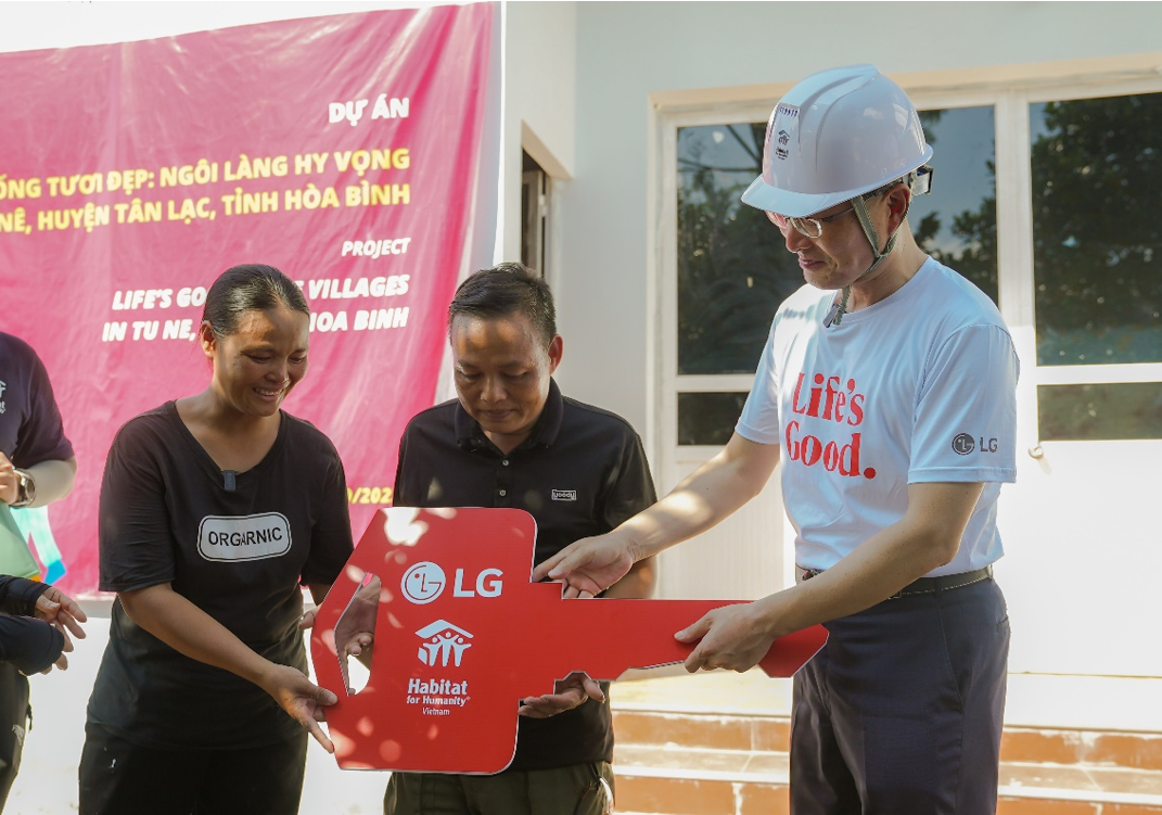 Song Ik-hwan, managing director of LG Electronics Vietnam, handing over a house key to a Muong family