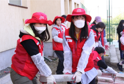 Two Life's Good volunteers moving a heavy brick together