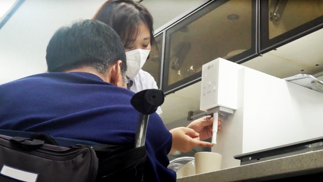 A man and a woman are testing the Easy Nozzle Kit applied to the LG water purifier