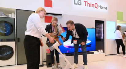 At IFA 2023, a woman on the left is holding the LG CordZero™ vacuum cleaner with Universal UP Kit applied, while a man and a woman are taking photos