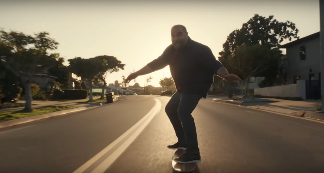 A photo of a man riding a longboard on the street