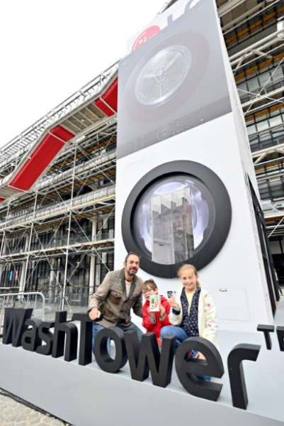 A family posing for a photo in front of a giant WashTower structure installed at Paris