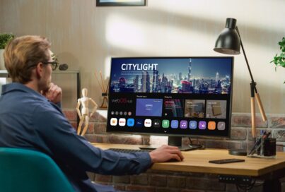 A man sitting at a desk explores the home UI of the new webOS Hub 2.0S on an LG smart monitor