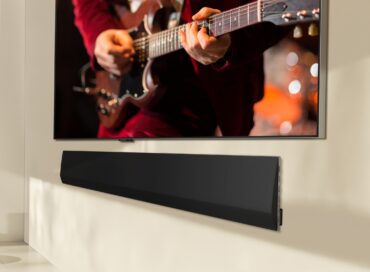 LG’s 2024 new soundbar model is wall mounted under an LG OLED TV that displays a man playing the guitar