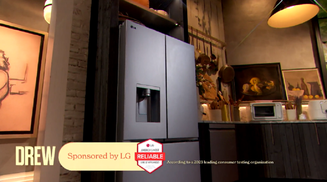 A photo of the LG refrigerator in the kitchen area with an LG sponsor label on the bottom