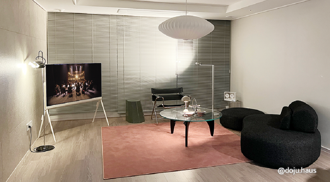 A photo of the LG Objet Collection Pose TV placed in the corner of a small living room area with a couch and table