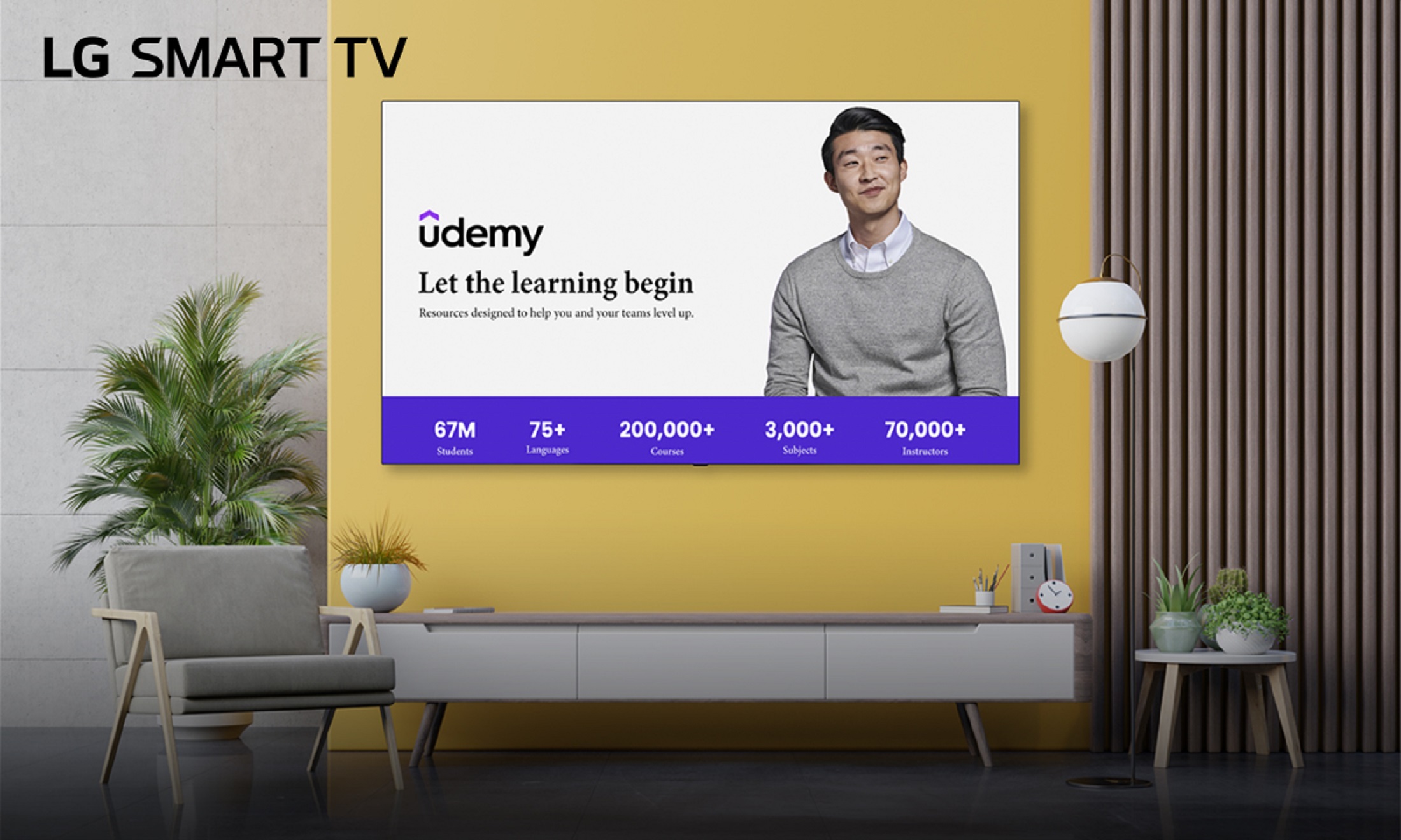 A wall-mounted LG Smart TV displays Udemy’s home screen