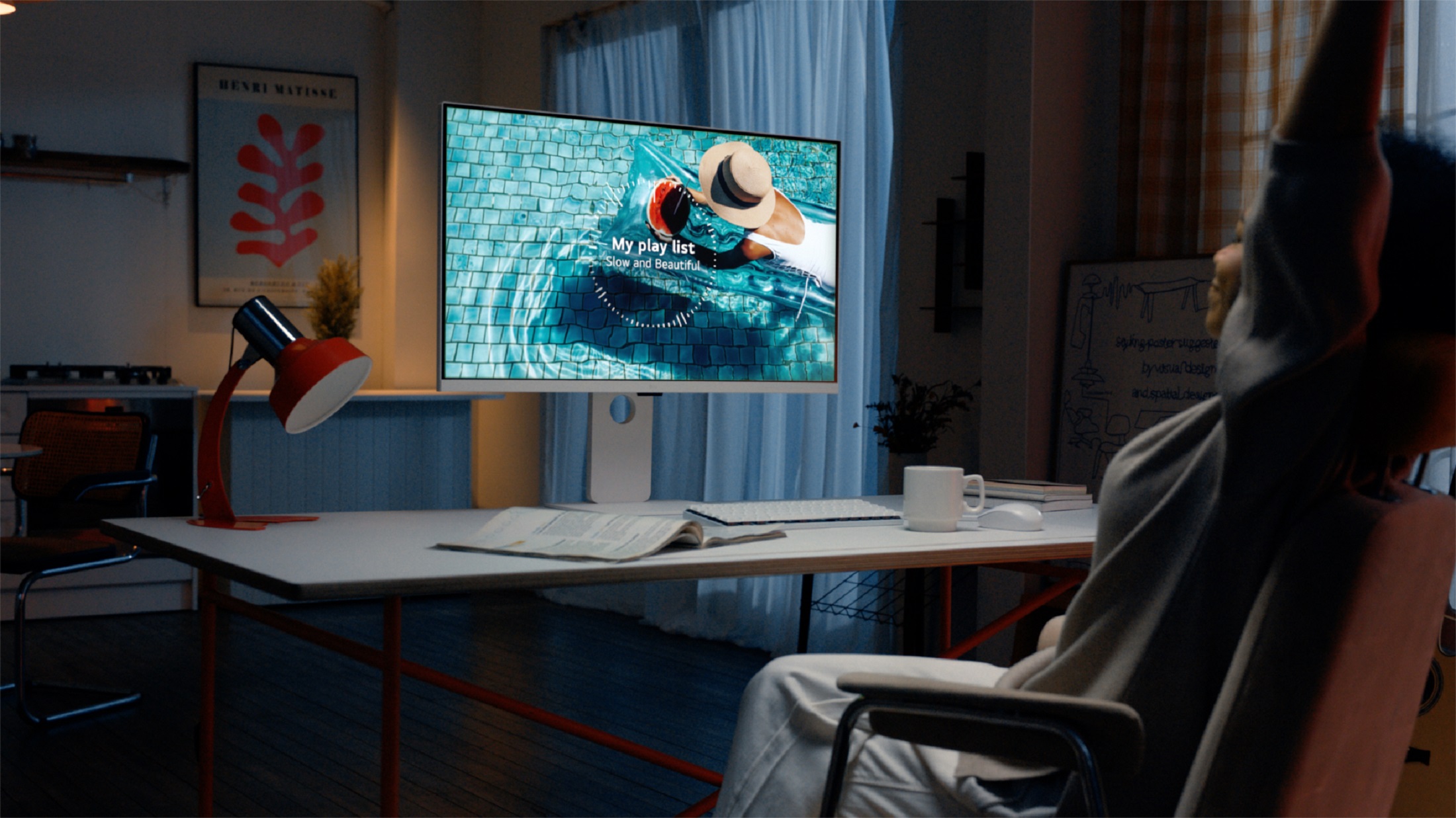 A user listening to a music playlist displayed on the LG MyView Smart Monitor at desk