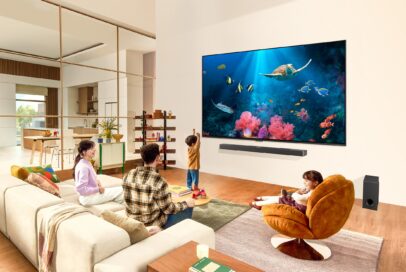 A family gathers around an ultra-large, wall-mounted LG QNED TV displaying an aquarium scene in their living room