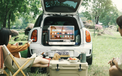 A photo a car trunk open with two people watching the LG StandbyME GO screen