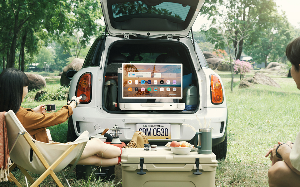 A photo a car trunk open with two people watching the LG StandbyME GO screen 