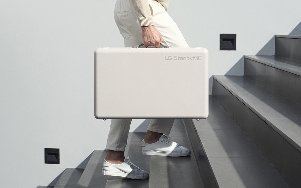 A photo of a person walking up the stairs while holding the folded LG StandbyME Go case