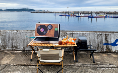 A photo of the LG StanbyME Go placed on a desk outside near the ocean