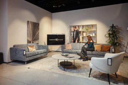 A photo of a woman sitting on a sofa and a man standing near the LG Objet Collection Pose