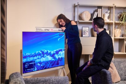 A close-up image of a woman touching the LG Objet Collection Pose with a man sitting nearby