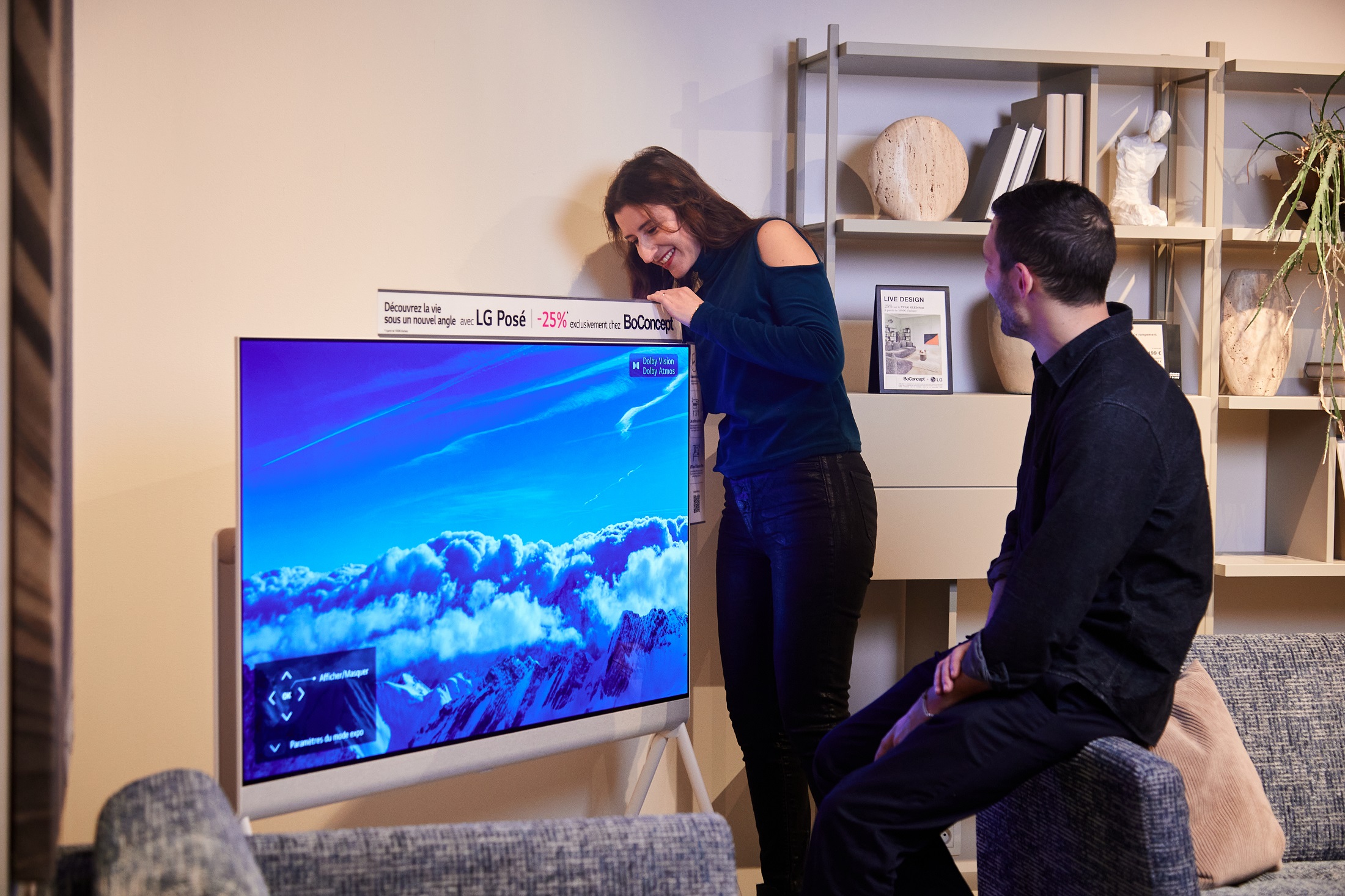 A close-up image of a woman touching the LG Objet Collection Pose with a man sitting nearby