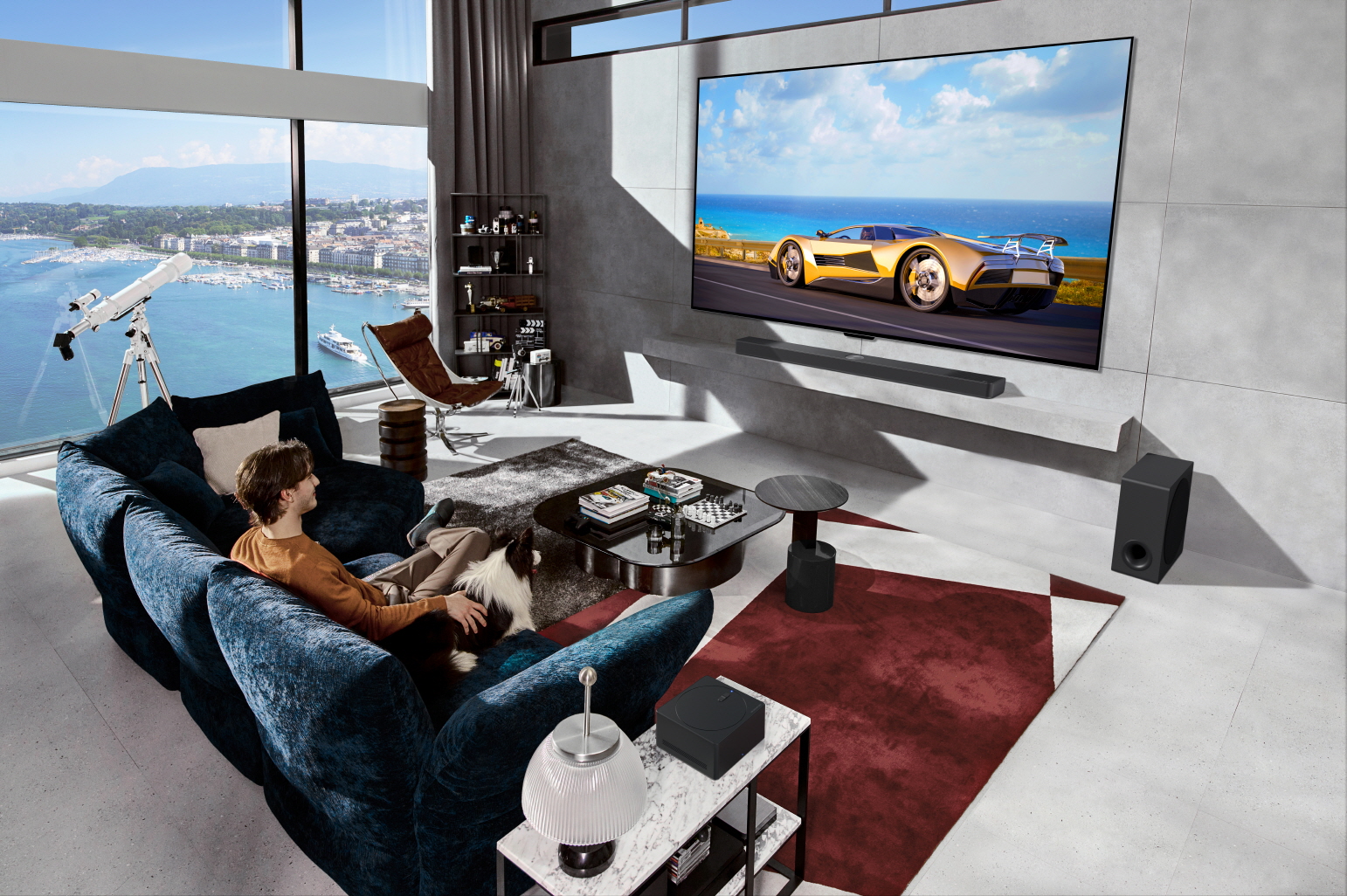 A car displayed on a wall-mounted LG OLED evo M4 captures the attention of a man and his border collie