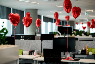 A photo of red heart balloons attached to workers' desks