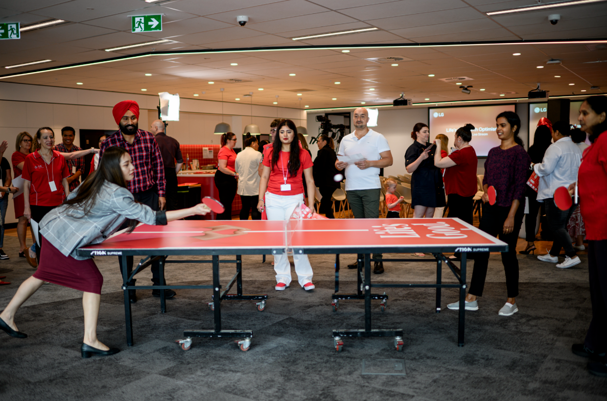 An image of people playing ping poing gathered around