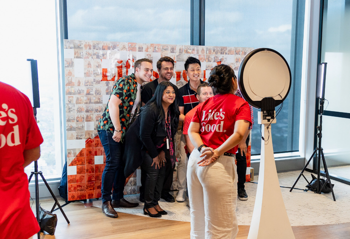 An image of people taking a picture together in front of a LG logo photo wall