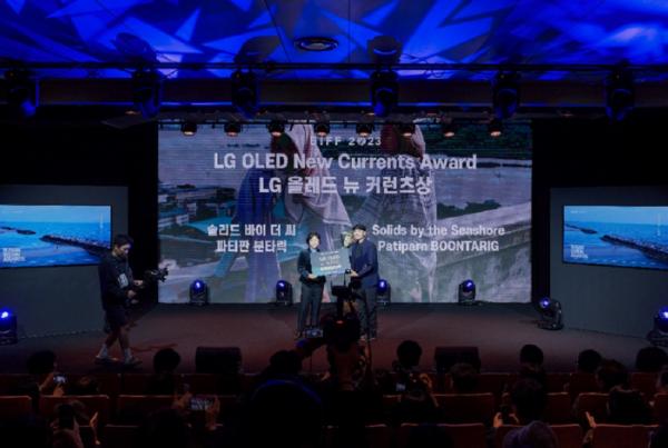 A photo of two people on stage receiving the LG OLED New Currents Award