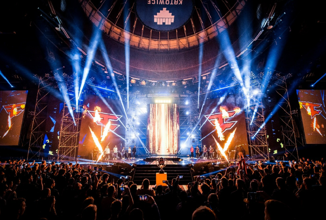 An image of the stage with lights and fireworks with players on stage