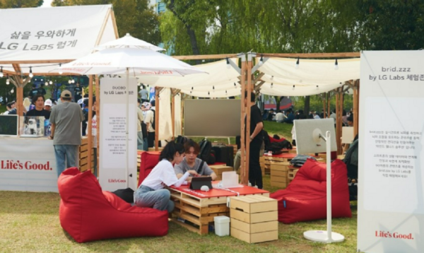 A picture of LG Labs offline experience zone with people sitting on the floor doing activities