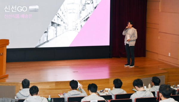 A picture of a man standing on stage and presenting to the crowd