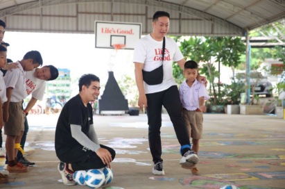 A picture of a man kicking a ball with a child