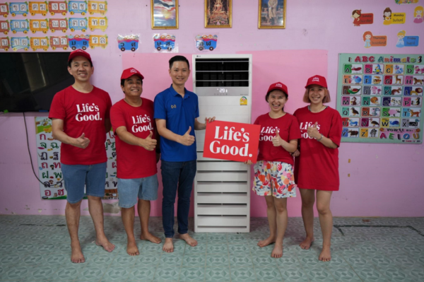 A picture of five people standing next to an LG air conditioner with the LG logo sign