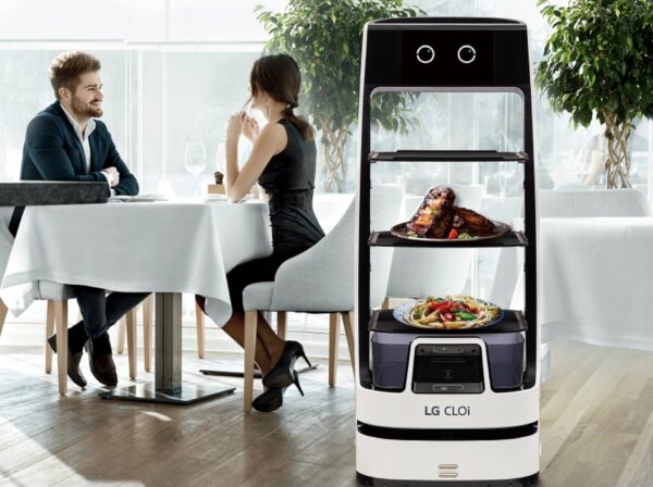A picture of a man and a woman at a restaurant next to a LG CLOi ServeBot with food