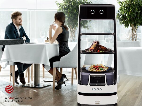 A picture of a woman and a man at a restaurant with the LG CLOi ServeBot next to them