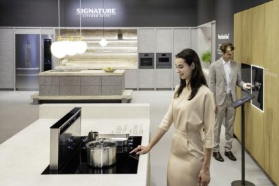 A photo of a woman and a man experiencing a built-in oven and induction hob in the SIGNATURE KITCHEN SUITE Kitchen zone at Salone del Mobile
