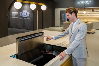 A photo of a man experiencing a free zone induction hob in the SIGNATURE KITCHEN SUITE Kitchen zone at Salone del Mobile