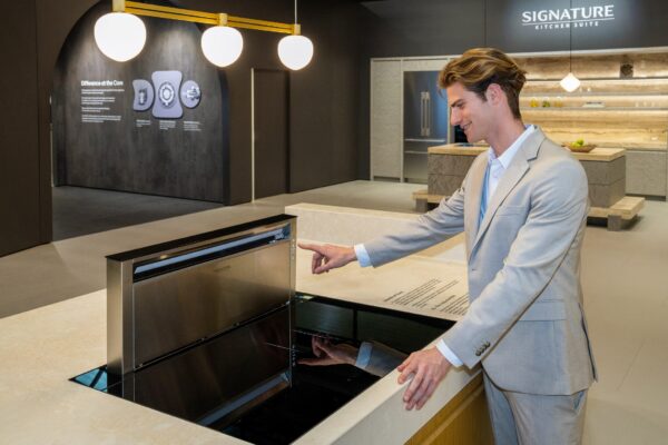 A photo of a man experiencing a free zone induction hob in the SIGNATURE KITCHEN SUITE Kitchen zone at Salone del Mobile 