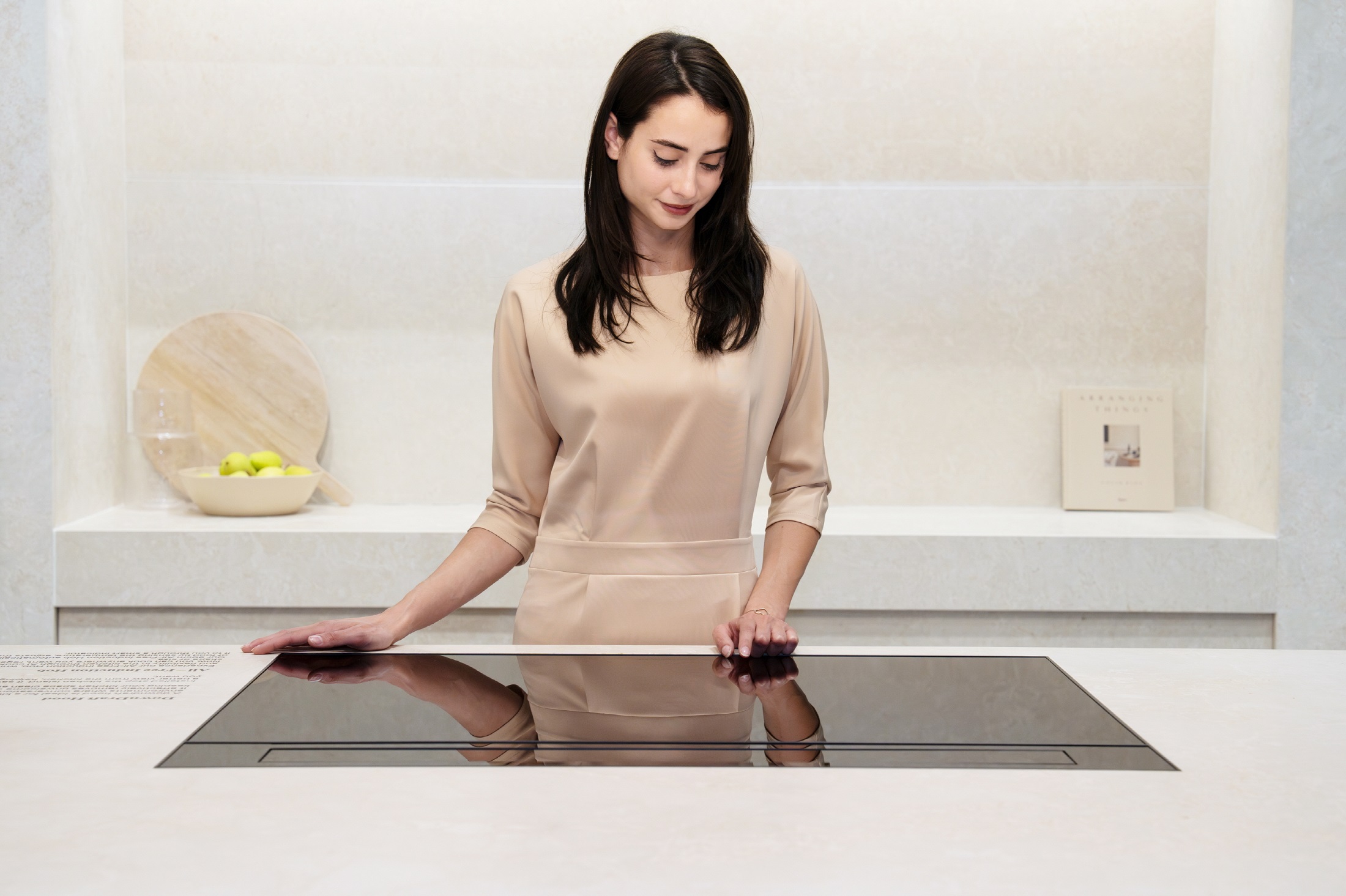 A photo of a woman experiencing a free zone induction hob in the SIGNATURE KITCHEN SUITE Kitchen zone at Salone del Mobile
