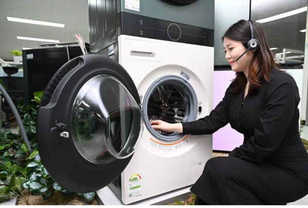 A woman with headphones on sitting next to a washer