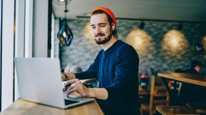 A man is using T90S earbuds while working on his laptop in a cafe