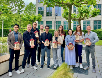 a photo of several smiling people holding insect hotel on their hand