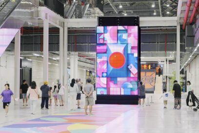 A picture of the kinetic LED signage displaying artwork with people walking by