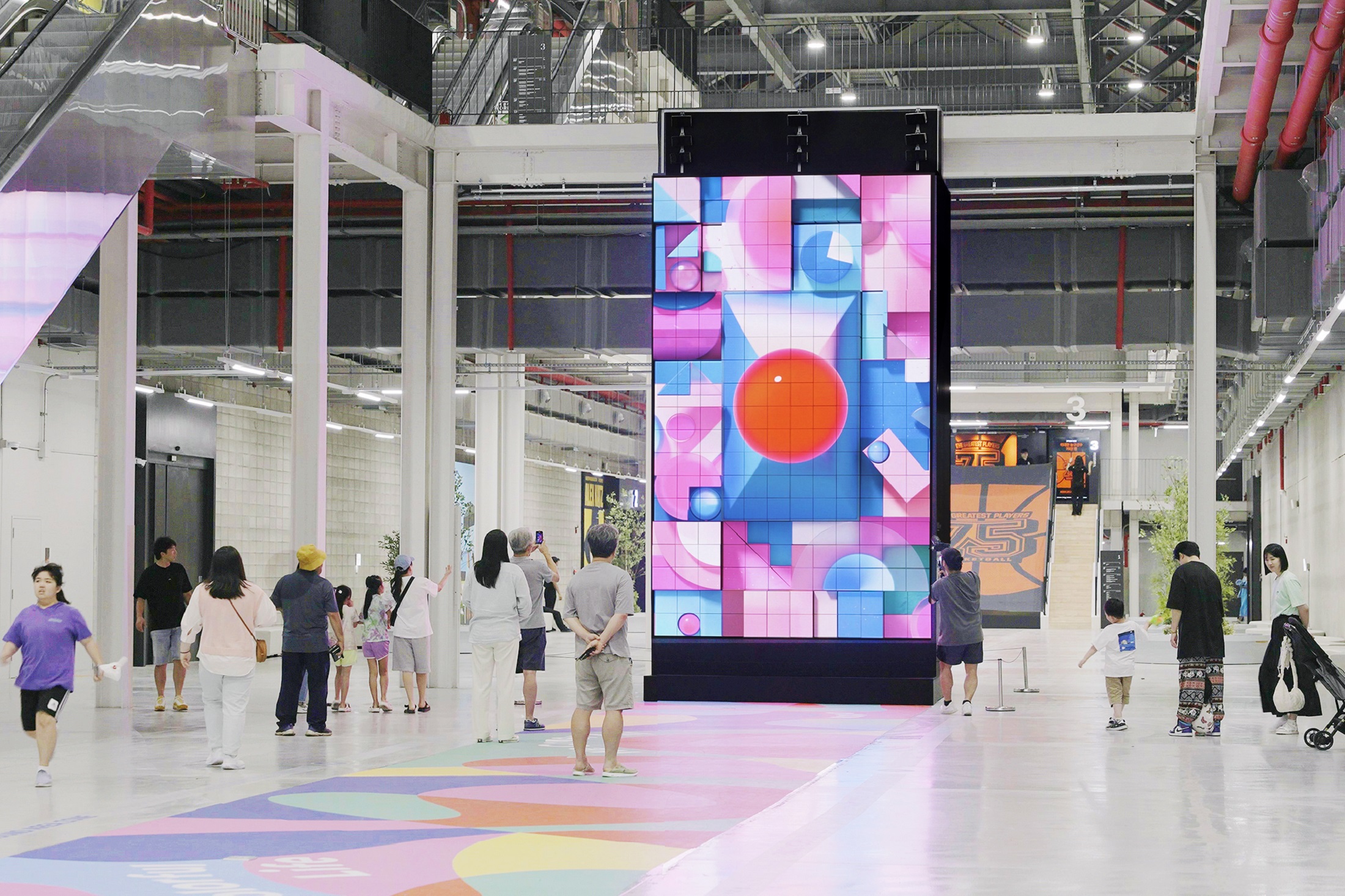 A picture of the kinetic LED signage displaying artwork with people walking by