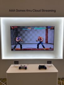 A 1 vs 1 fighting game is displayed on a wall-mounted monitor, with two controllers labeled BT Legacy and BT ULL on a table in front of the screen
