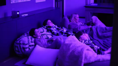A family lying on the bed and watching content projected from the LG CineBeam Q projector