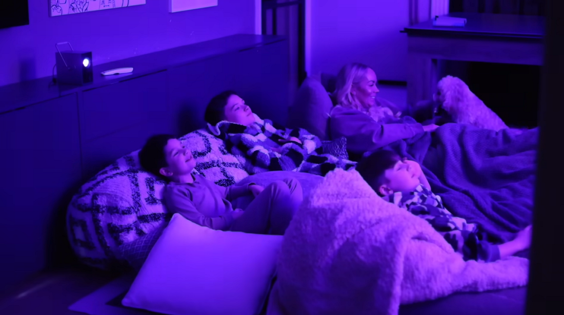A family lying on the bed and watching content projected from the LG CineBeam Q projector