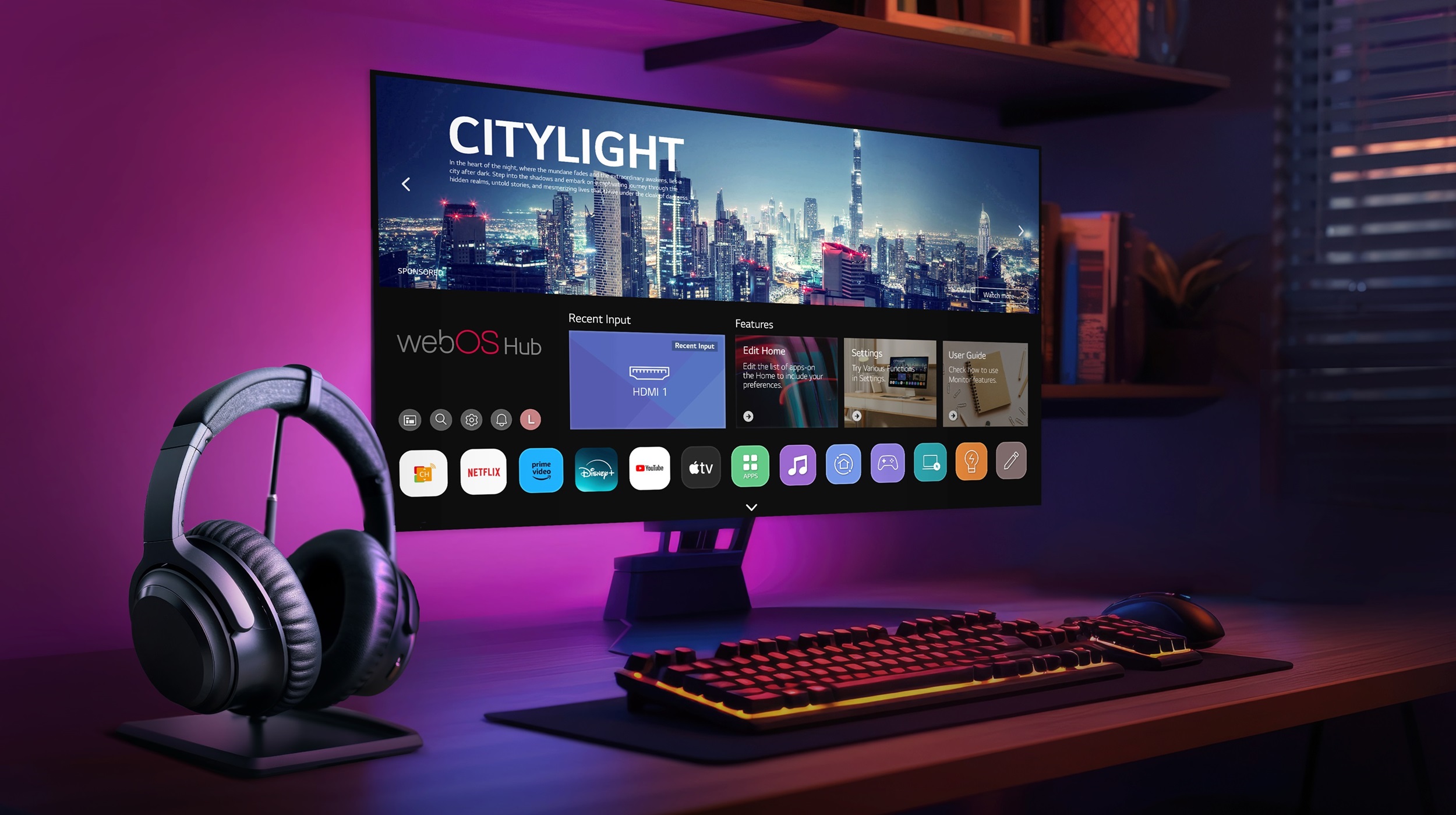 The monitor of a gaming setup displays the webOS Hub platform, with wireless headphones placed beside the keyboard